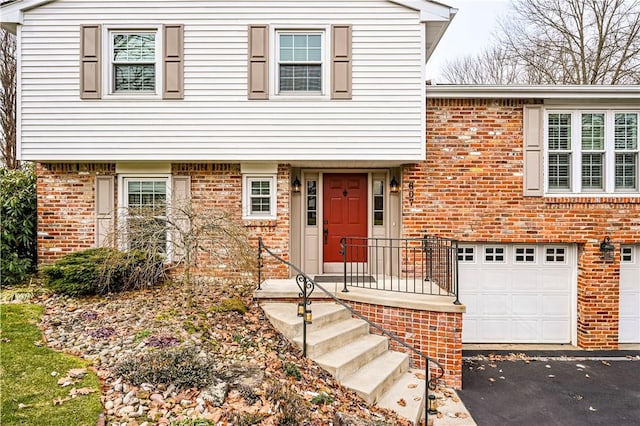 view of front of property featuring a garage, brick siding, and driveway