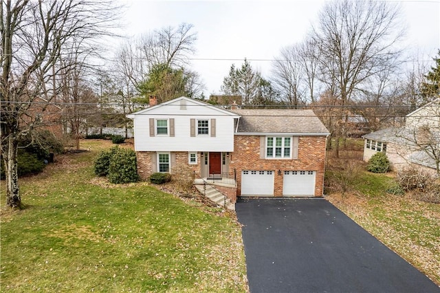 tri-level home featuring aphalt driveway, a front yard, brick siding, and an attached garage