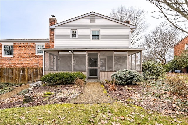 rear view of house with fence, a sunroom, and a chimney