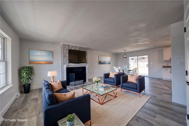 living area with a fireplace, wood finished floors, and baseboards