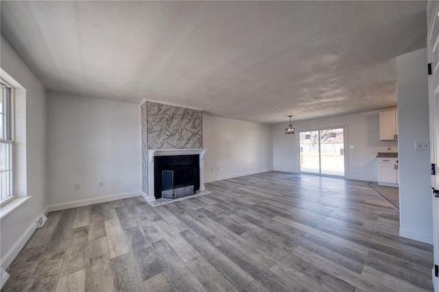 unfurnished living room with wood finished floors, a fireplace, and baseboards