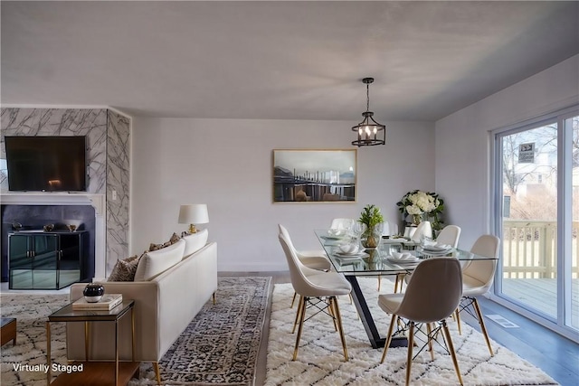 dining space with a high end fireplace, a chandelier, and wood finished floors