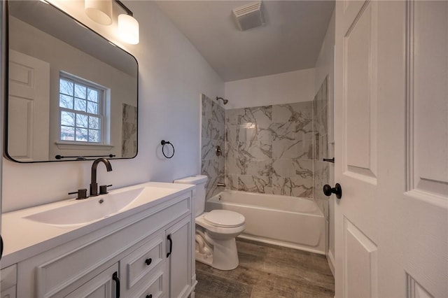 bathroom featuring visible vents, toilet, wood finished floors, tub / shower combination, and vanity