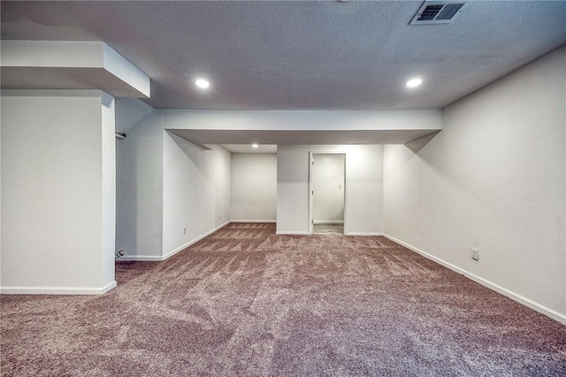 finished below grade area featuring visible vents, a textured ceiling, recessed lighting, carpet flooring, and baseboards