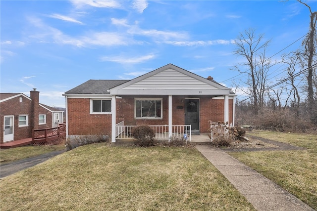 bungalow-style home featuring brick siding, a porch, a front yard, and roof with shingles