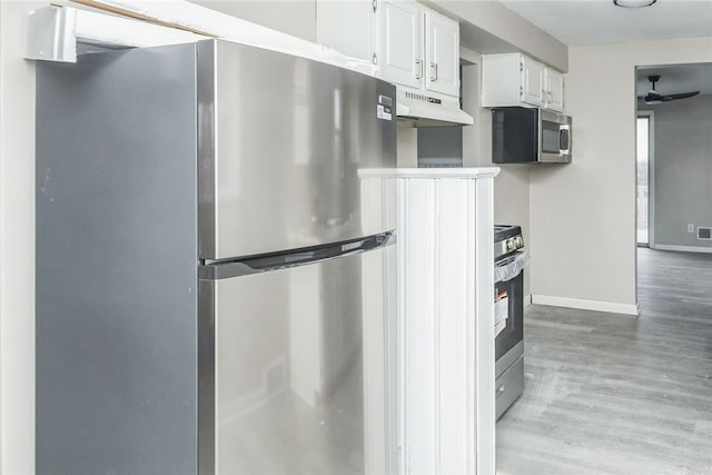 kitchen with a ceiling fan, light wood finished floors, under cabinet range hood, appliances with stainless steel finishes, and white cabinetry