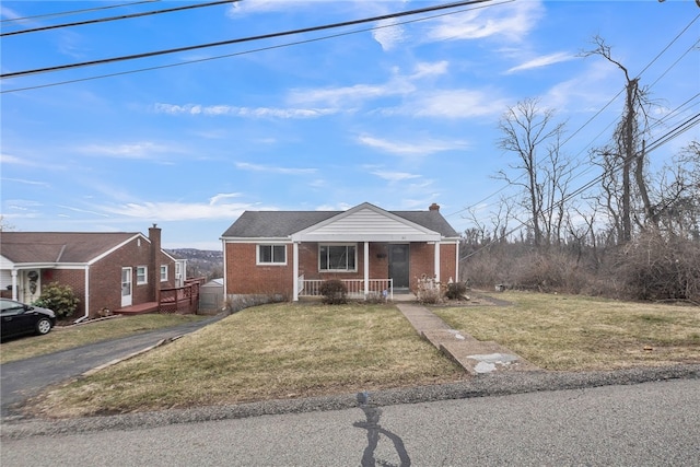 bungalow-style house with brick siding, covered porch, and a front lawn