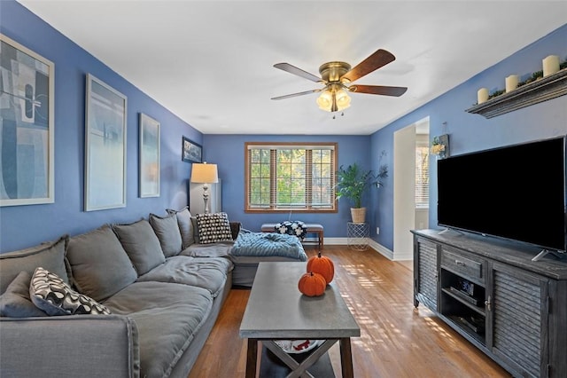 living area featuring baseboards, ceiling fan, and wood finished floors