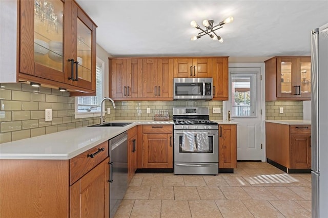 kitchen featuring a sink, appliances with stainless steel finishes, a wealth of natural light, and brown cabinetry