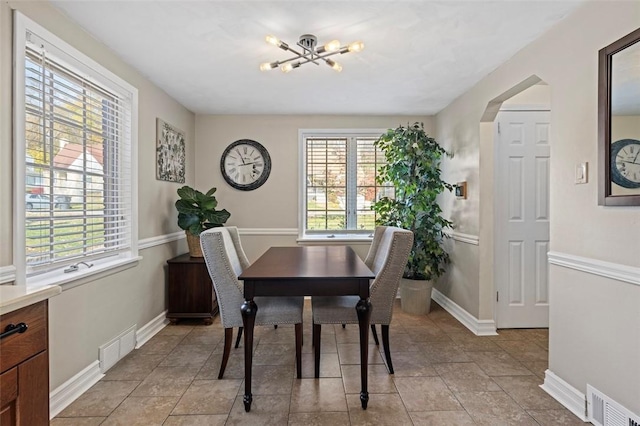 dining area with visible vents, arched walkways, a notable chandelier, and baseboards