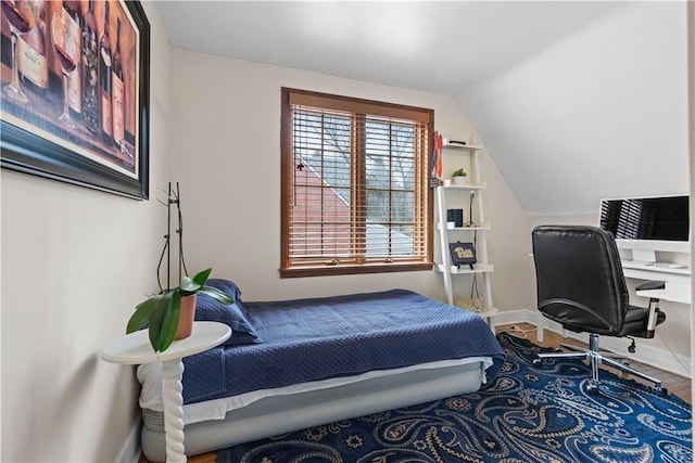 bedroom with lofted ceiling, wood finished floors, and baseboards