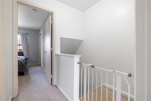 hallway with carpet flooring, an upstairs landing, and baseboards