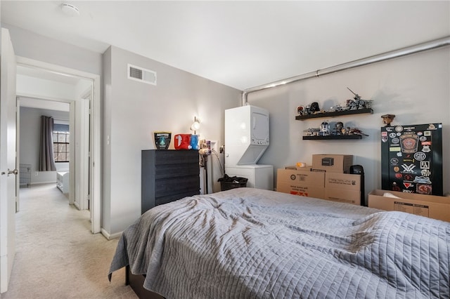 bedroom with visible vents, light colored carpet, stacked washer and clothes dryer, and baseboards