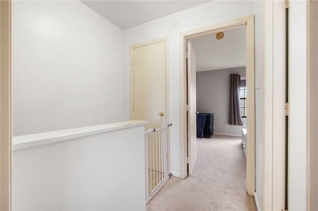 corridor featuring light colored carpet and baseboards