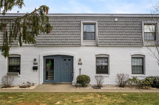 townhome / multi-family property featuring brick siding and mansard roof