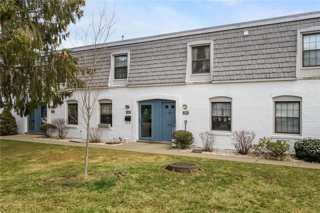 view of front of property featuring a front lawn, mansard roof, and brick siding