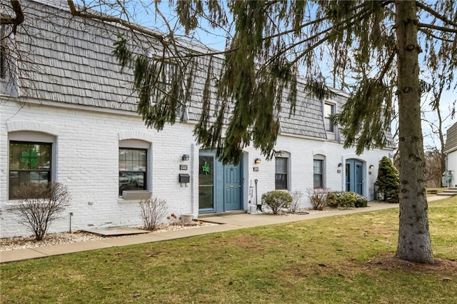 multi unit property featuring a front yard, mansard roof, and brick siding