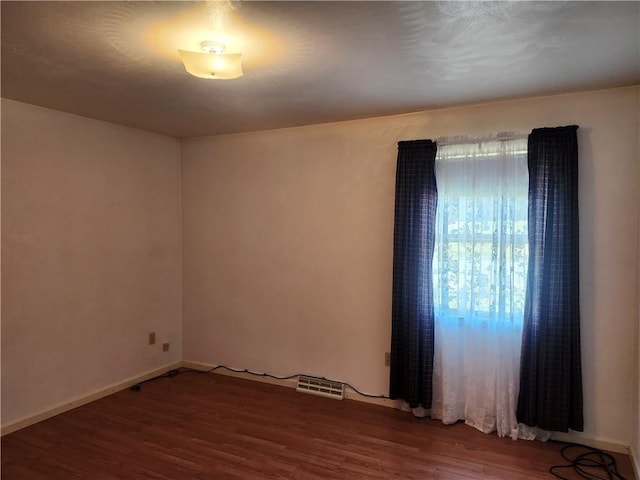 unfurnished room featuring visible vents, baseboards, and wood finished floors