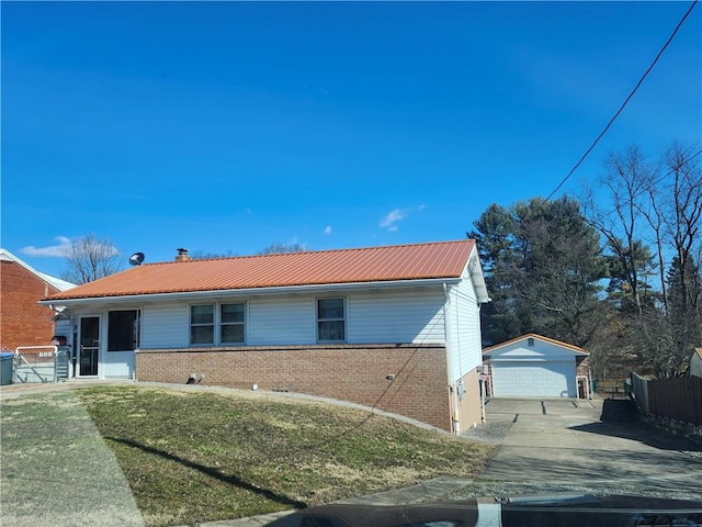 view of front of home featuring fence, an outdoor structure, a detached garage, brick siding, and metal roof