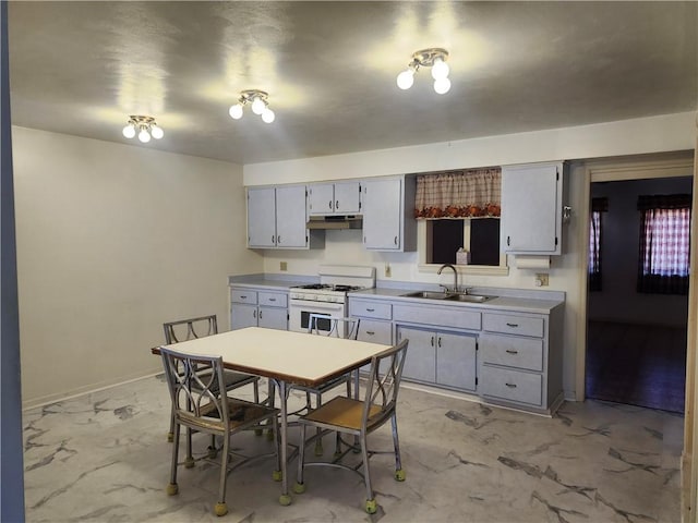 kitchen with marble finish floor, a sink, gas range gas stove, light countertops, and baseboards