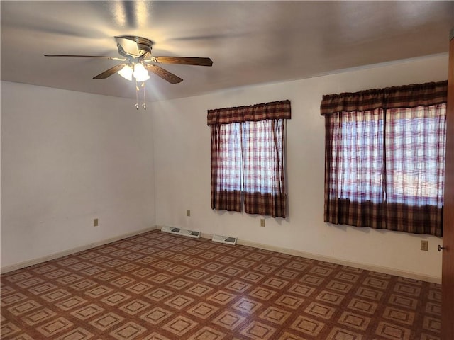 spare room with baseboards, visible vents, and ceiling fan