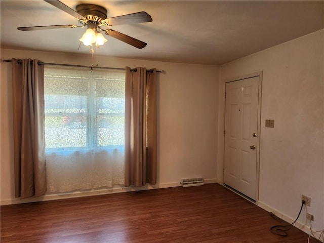 spare room with visible vents, a ceiling fan, baseboards, and dark wood-style flooring