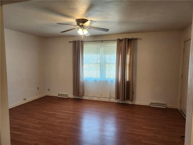 spare room with a ceiling fan, visible vents, dark wood-style flooring, and baseboards