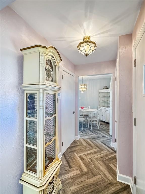 corridor with a notable chandelier and baseboards