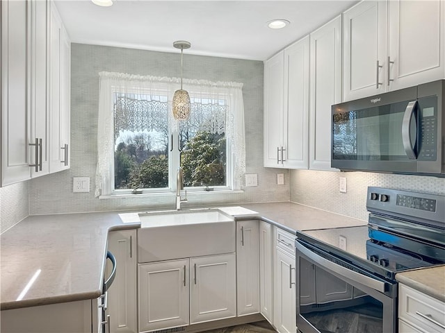 kitchen featuring stainless steel electric range oven, a sink, white cabinets, decorative light fixtures, and tasteful backsplash