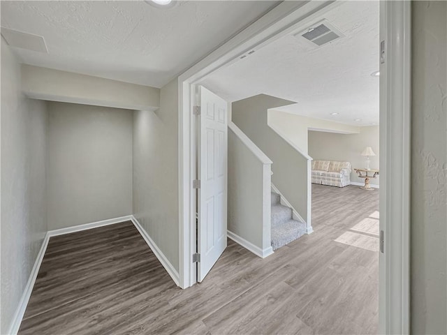 interior space with visible vents, baseboards, wood finished floors, and stairway