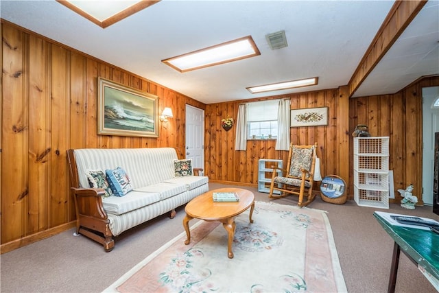 living room with wooden walls, visible vents, and carpet