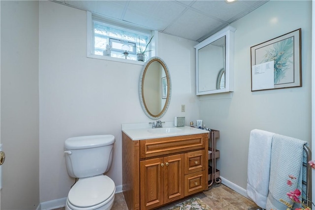 half bathroom featuring vanity, toilet, and baseboards