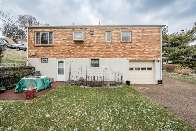 back of house featuring brick siding, driveway, an attached garage, and a yard