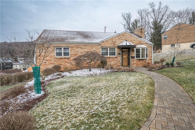 view of front of home featuring a front lawn, brick siding, a chimney, and a shingled roof