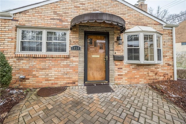 entrance to property with brick siding and a chimney