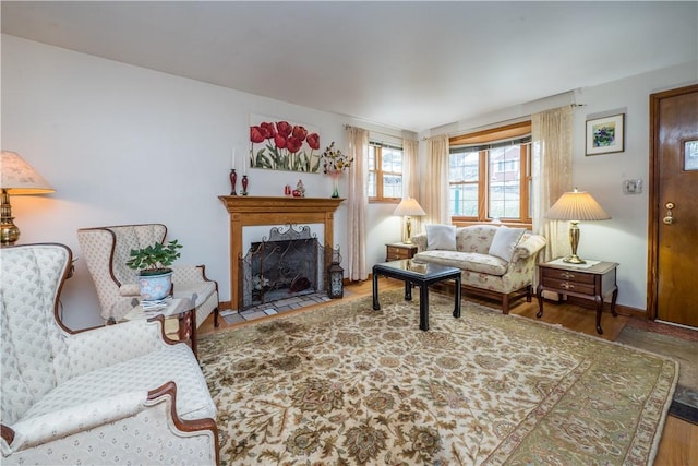 living room featuring baseboards, a fireplace with flush hearth, and wood finished floors