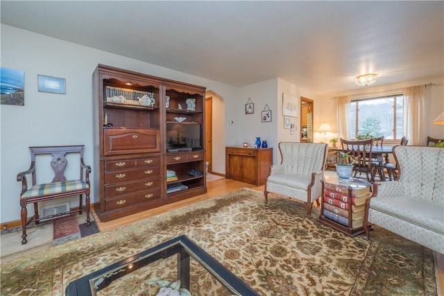 living room with baseboards, arched walkways, and wood finished floors