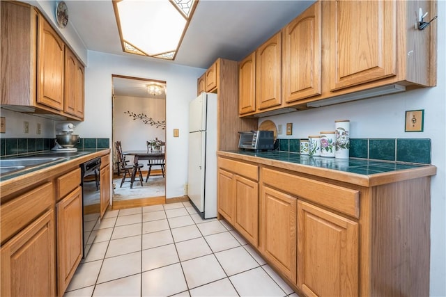 kitchen with a toaster, light tile patterned flooring, freestanding refrigerator, black dishwasher, and brown cabinets