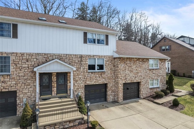 view of front facade featuring stone siding, driveway, a shingled roof, and an attached garage