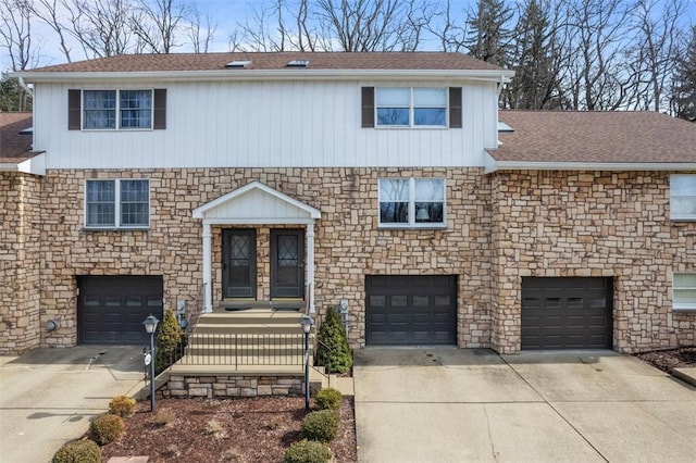 view of front of home featuring stone siding, an attached garage, concrete driveway, and a shingled roof