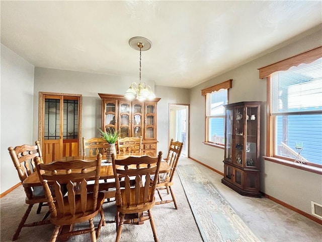 dining room with visible vents, light colored carpet, baseboards, and an inviting chandelier