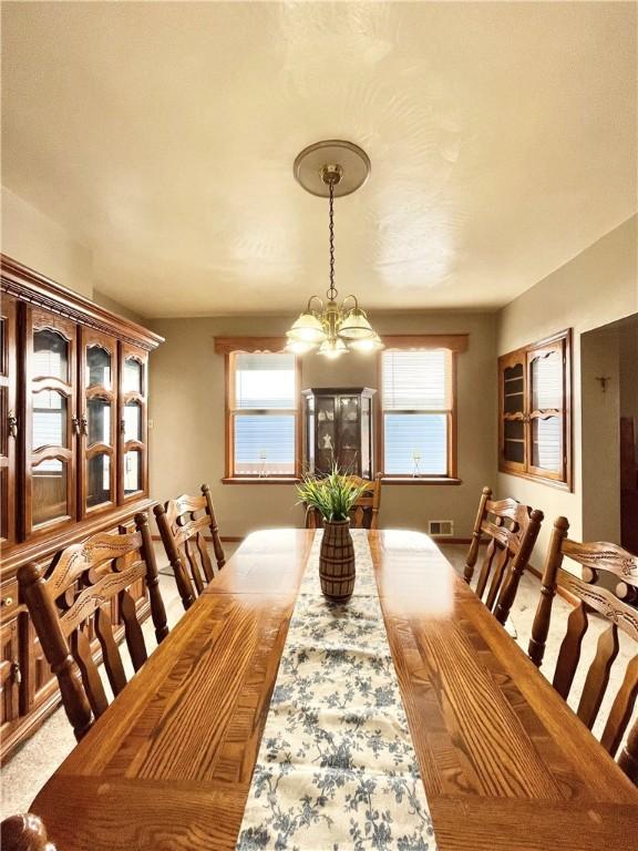 carpeted dining space with a notable chandelier and visible vents