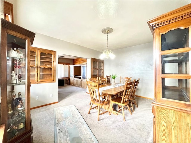 dining area featuring light colored carpet, baseboards, and an inviting chandelier