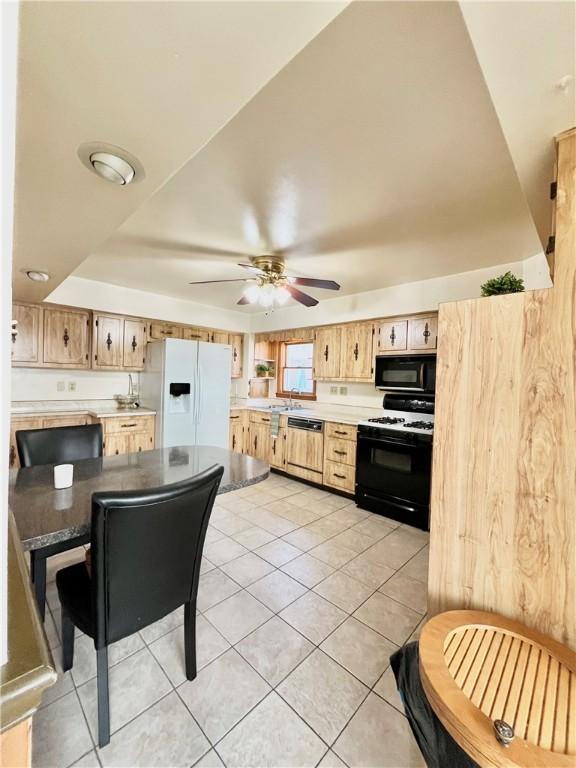 kitchen featuring black microwave, light tile patterned floors, paneled dishwasher, white refrigerator with ice dispenser, and gas stove