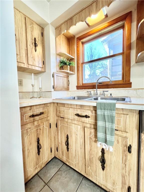 kitchen featuring a sink, open shelves, light countertops, and light brown cabinetry