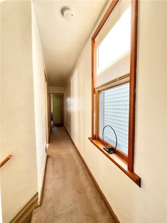 corridor featuring light carpet and baseboards