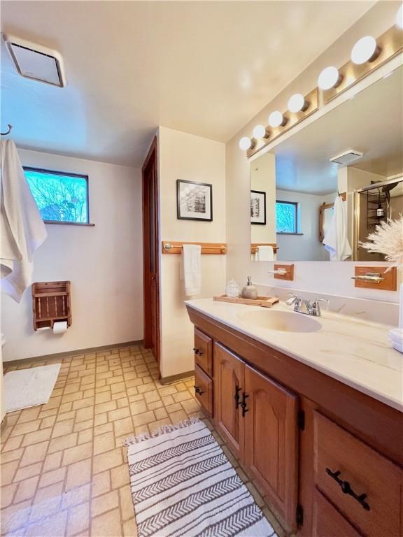 full bathroom with visible vents, a stall shower, vanity, and brick floor