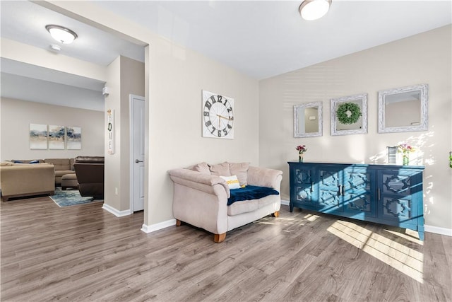 sitting room featuring baseboards, lofted ceiling, and wood finished floors