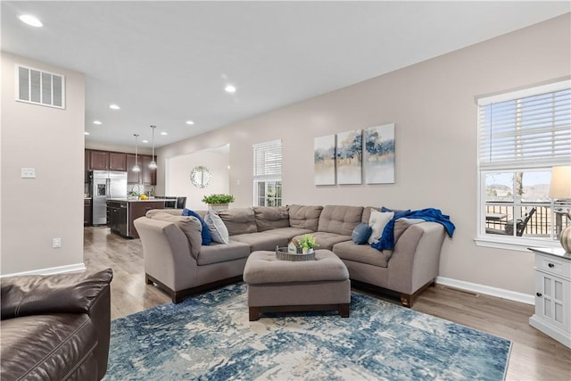 living room featuring recessed lighting, baseboards, visible vents, and light wood finished floors