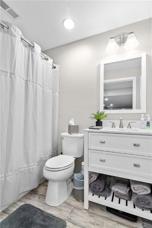 bathroom featuring vanity, a shower with curtain, wood finished floors, visible vents, and toilet